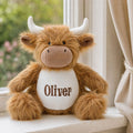 Boy cuddling a personalised Highland Cow plush Oliver with embroidered name