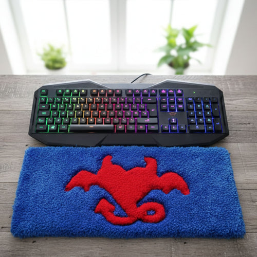 Handmade tufted keyboard rug featuring playful blue devil heart with red wings