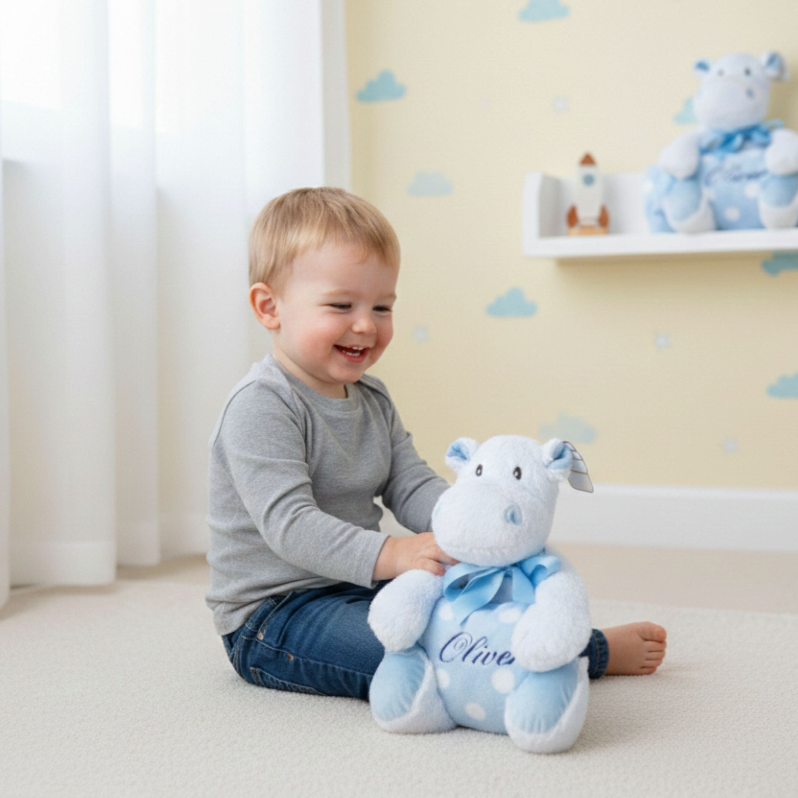 Little boy playing with personalised blue hippo Sky soft toy with blanket