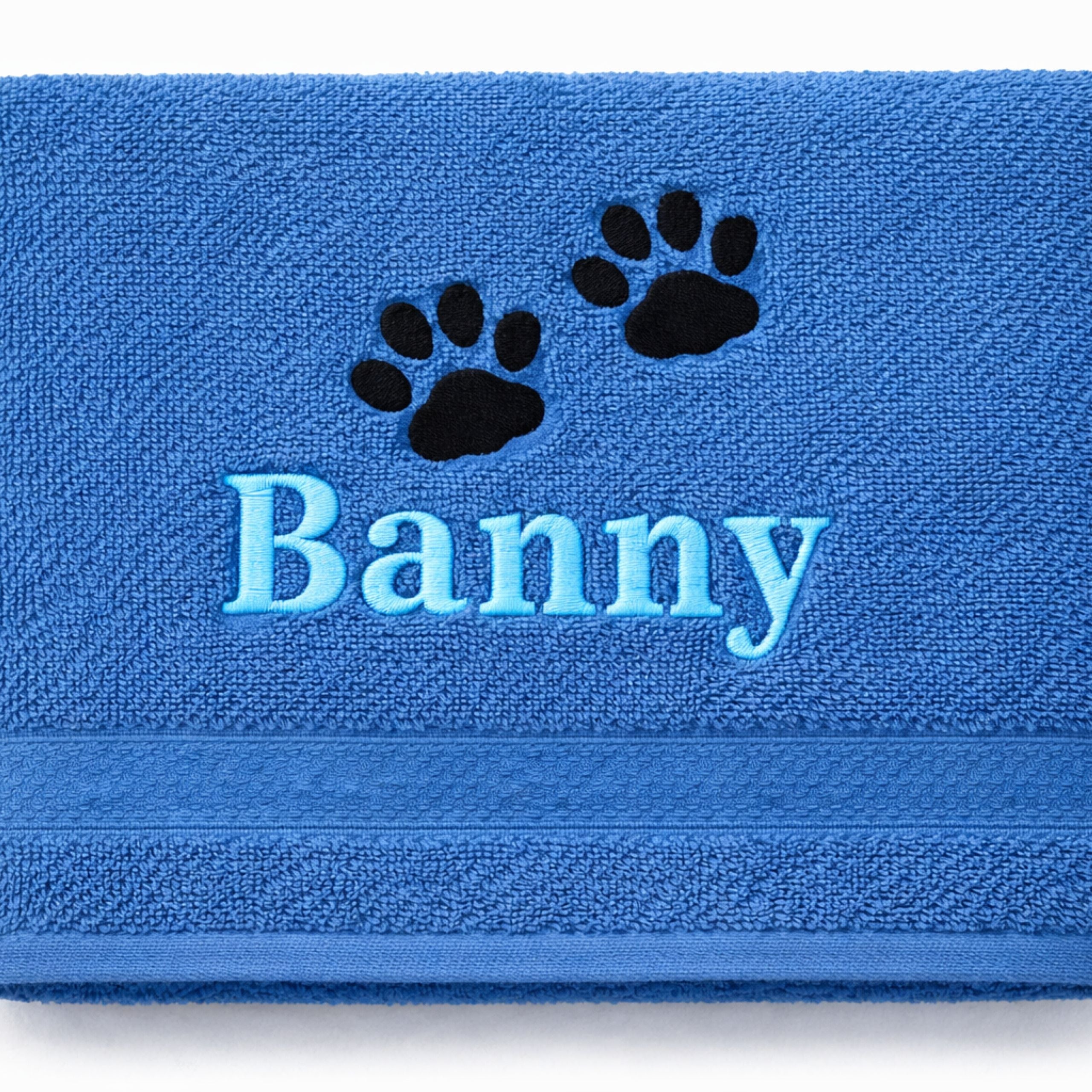 Close-up of embroidered dog name with paw prints on cotton towel