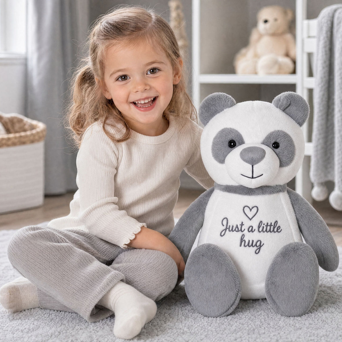 Little girl sitting on the floor holding Chester the personalised panda plush in her arms