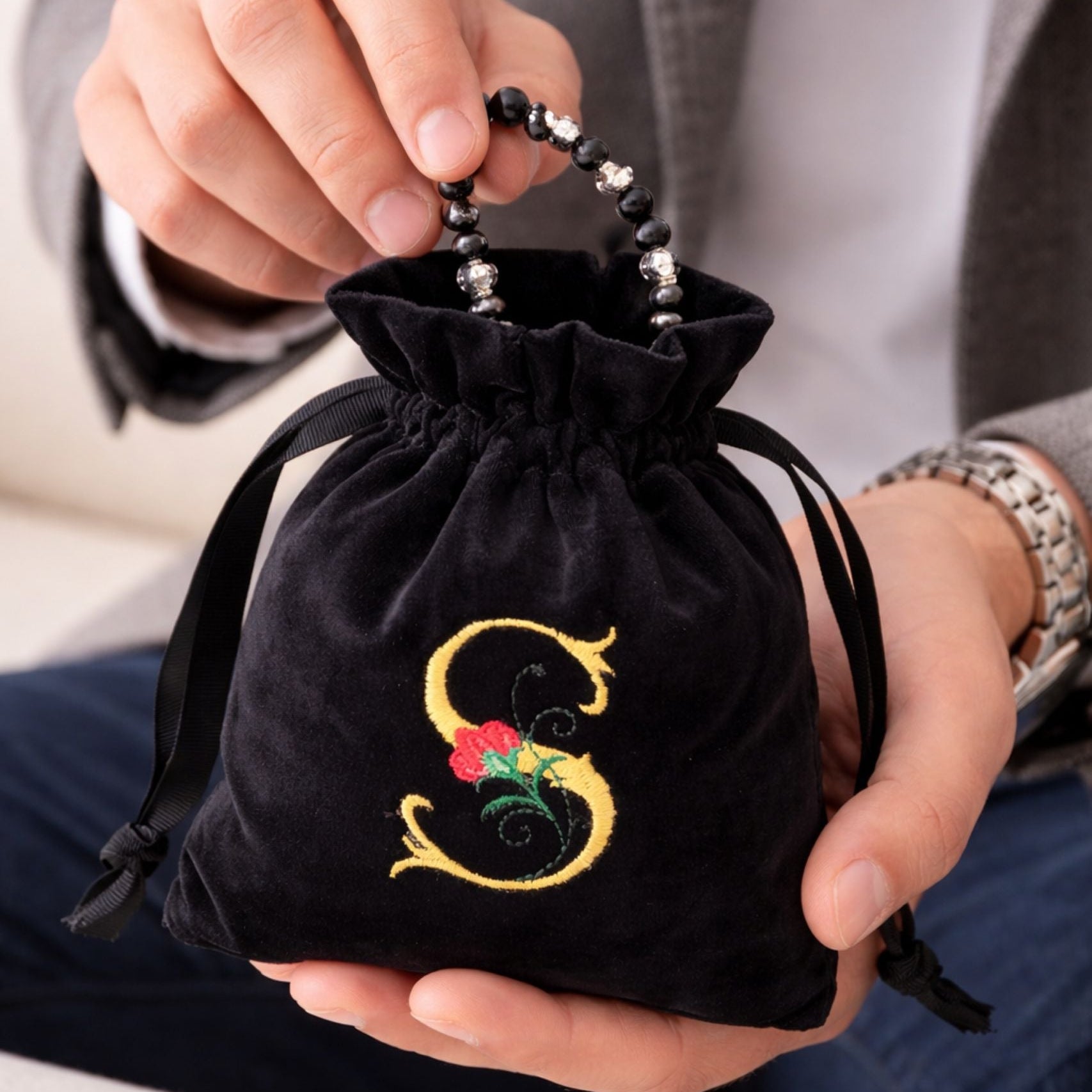 Mens hands holding personalised velvet gift bag with custom embroidery
