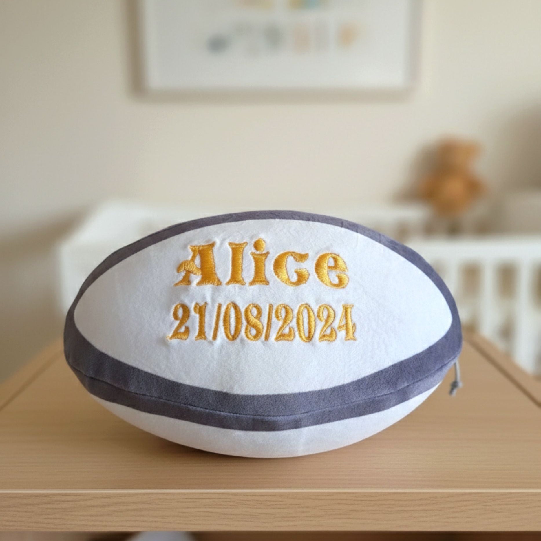 Side view of a soft plush rugby ball personalised with a custom embroidered name
