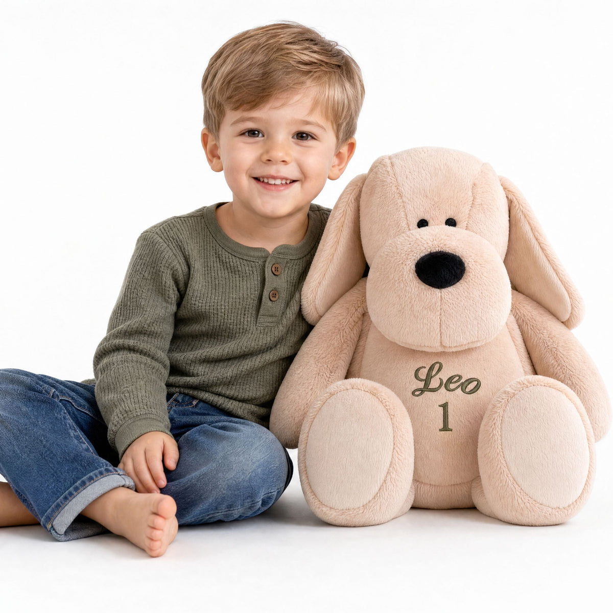 Personalised plush dog Pip sitting beside a little boy on a carpet