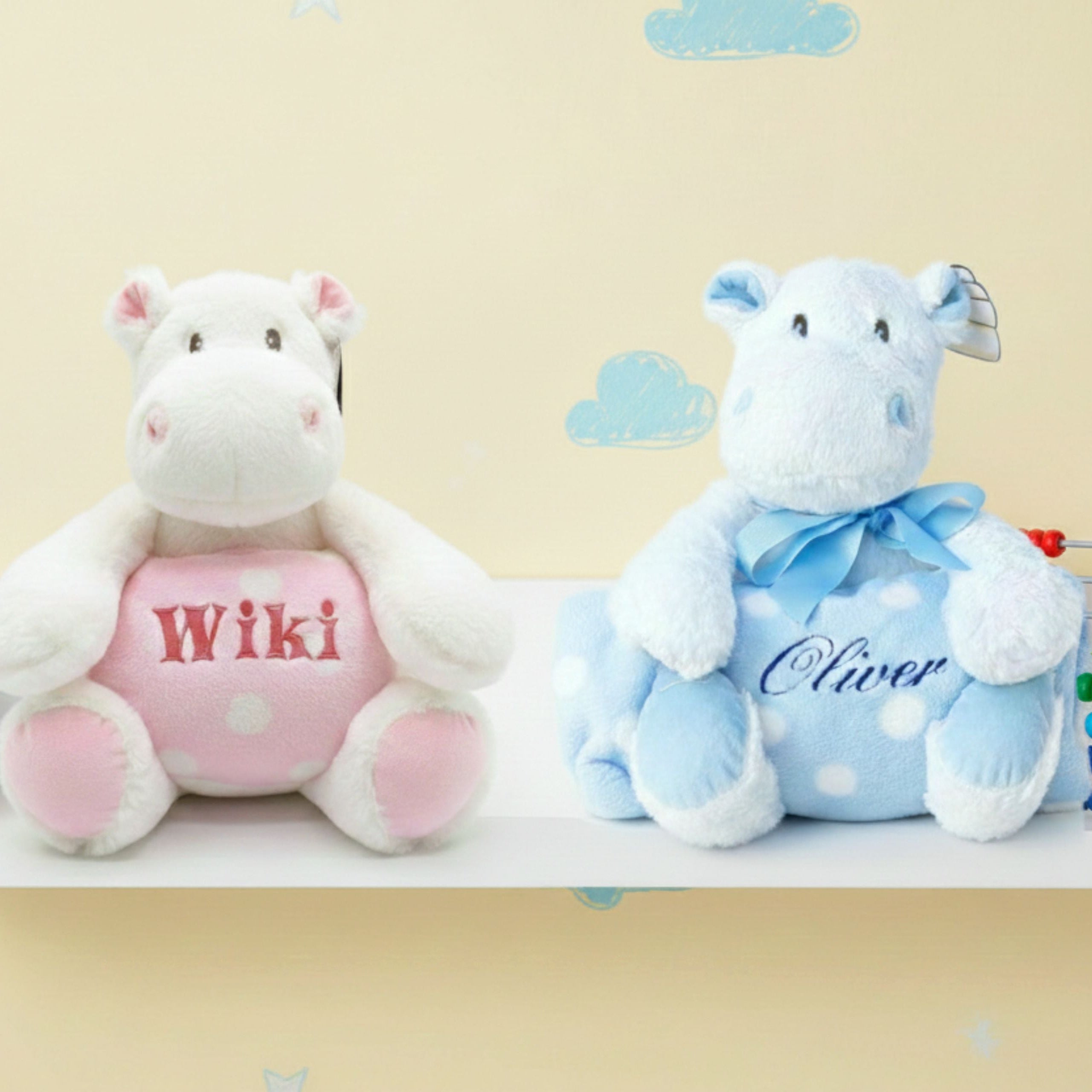 Pink and blue personalised hippos with fleece blankets sitting on nursery shelf