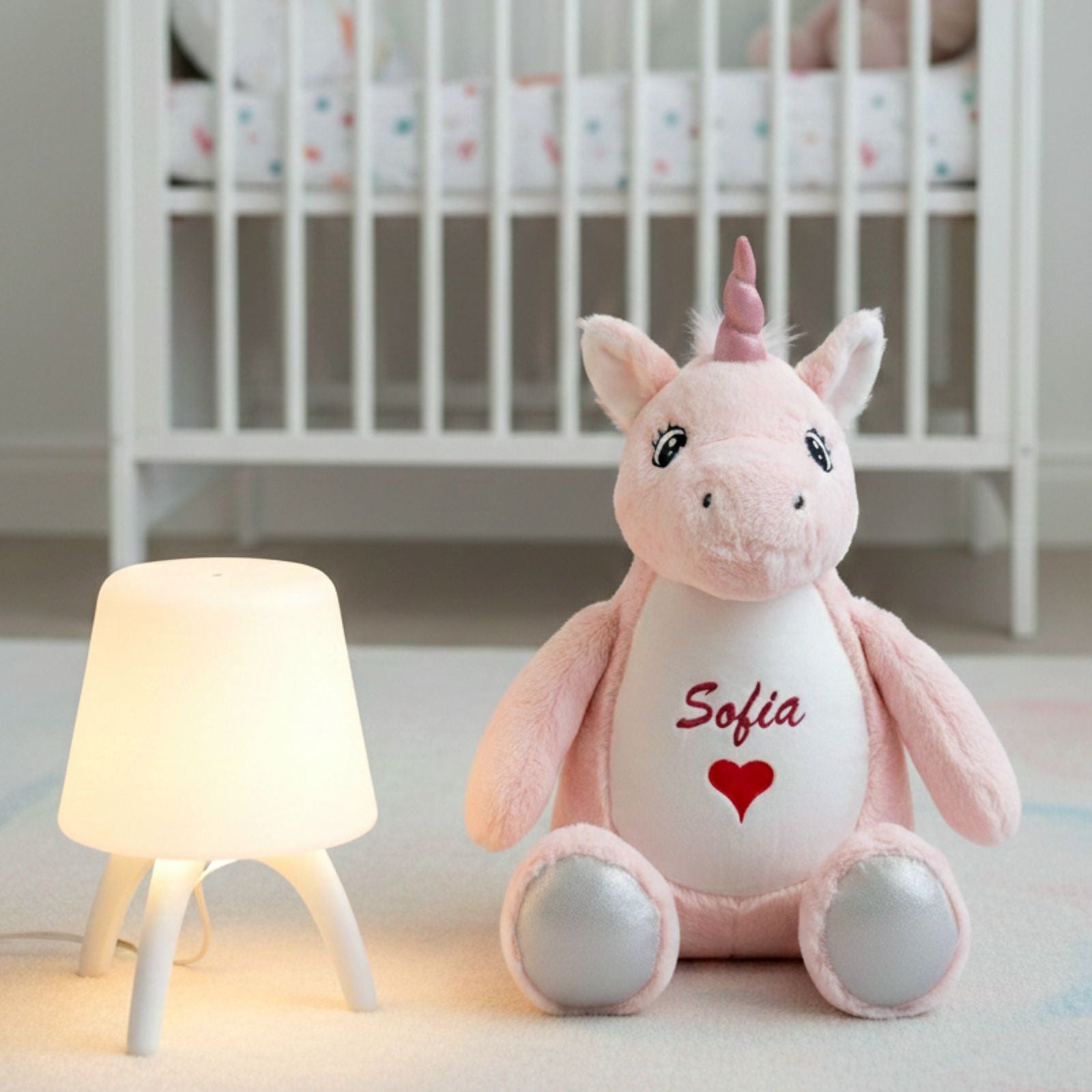 Luna the pink plush unicorn sitting on the floor in a child’s bedroom