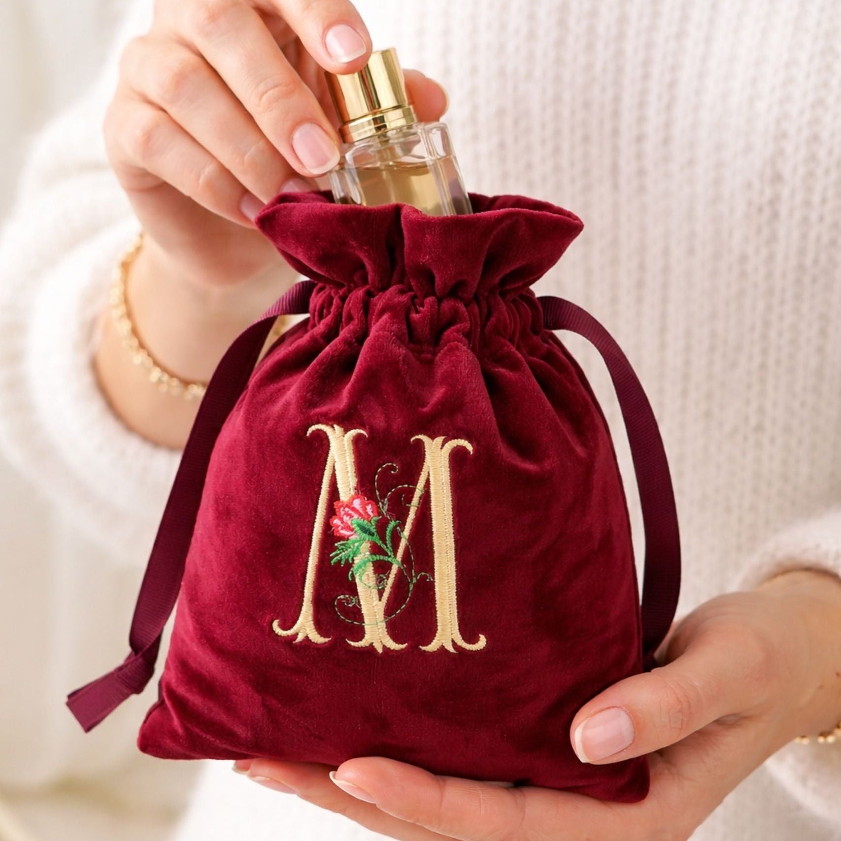 Womens hands holding personalised velvet gift bag with embroidered initial